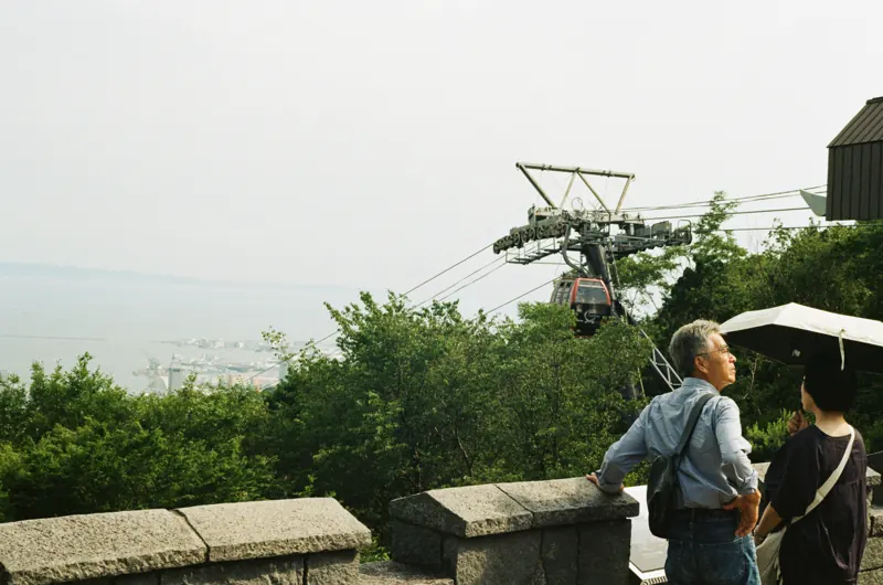 Visitors watching a cable car from a mountain viewpoint