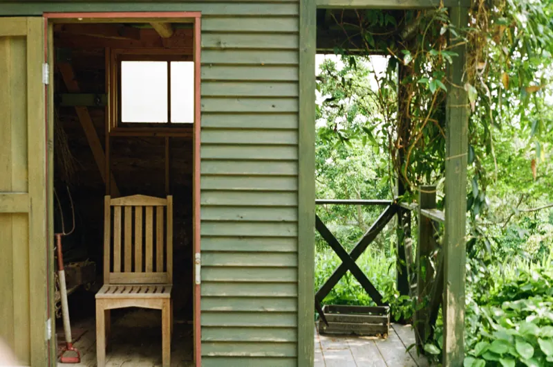 An open doorway and wooden chair beside a garden